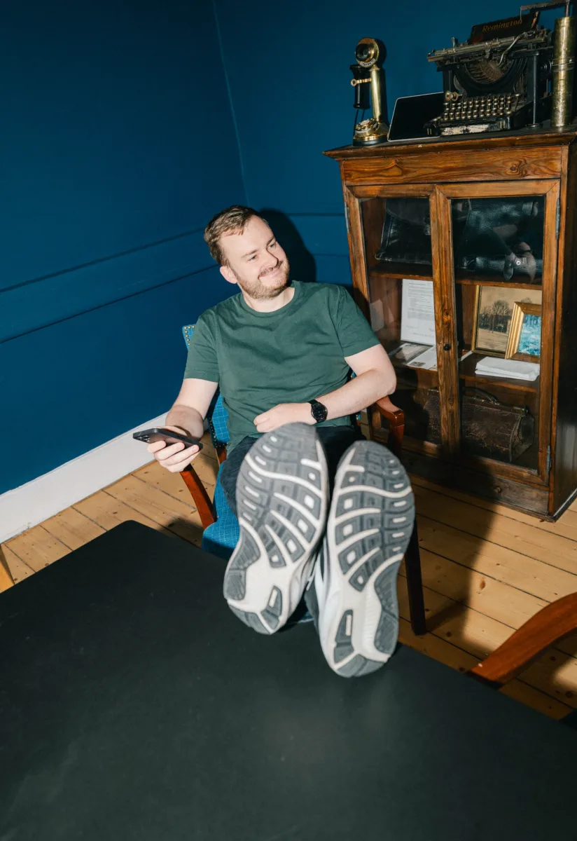 Medarbejder sidder med benene oppe på et bord og en telefon i hånden