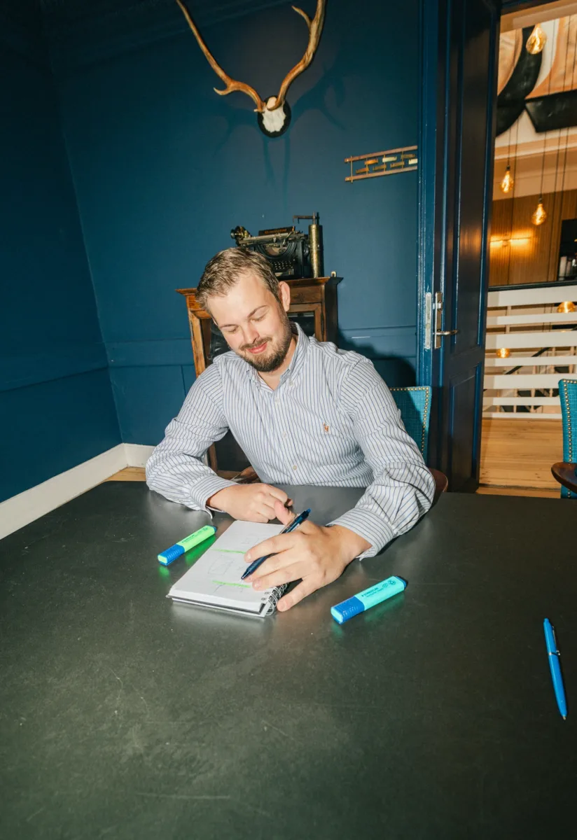 Medarbejder tegner en skitse i en notesblok ved et mødebord