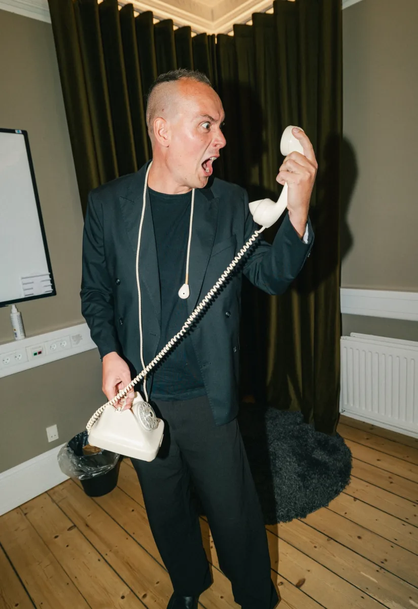 Medarbejder råber ind i telefonrøret på en gammel drejeskivetelefon