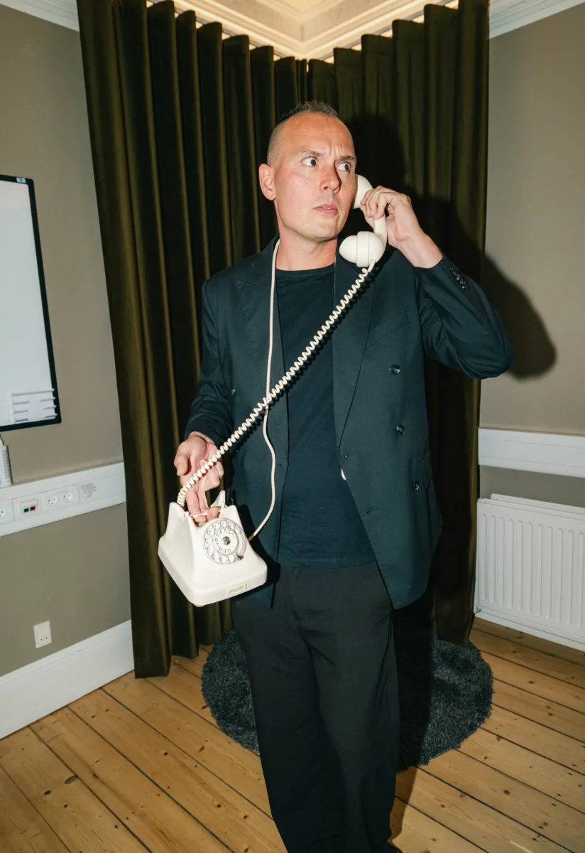 Medarbejder kigger til siden med telefonrøret ved øret i et mødelokale