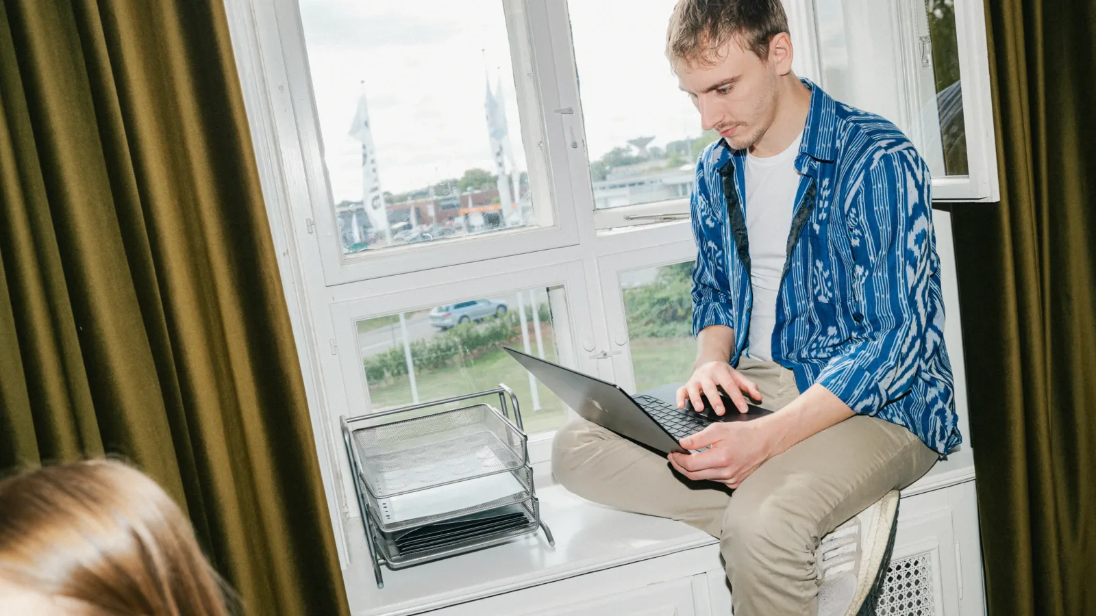 Medarbejder sidder i en vindueskarm og arbejder på en bærbar computer