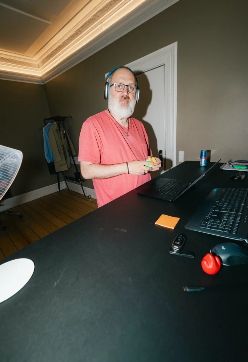 Medarbejder drejer på en Rubiks terning og kigger mod kameraet ved skrivebordet