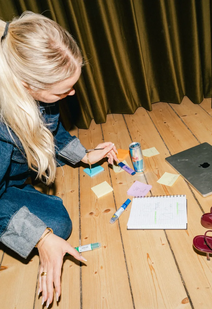 Medarbejder sidder på gulvet og arbejder med farvede post-its og markers