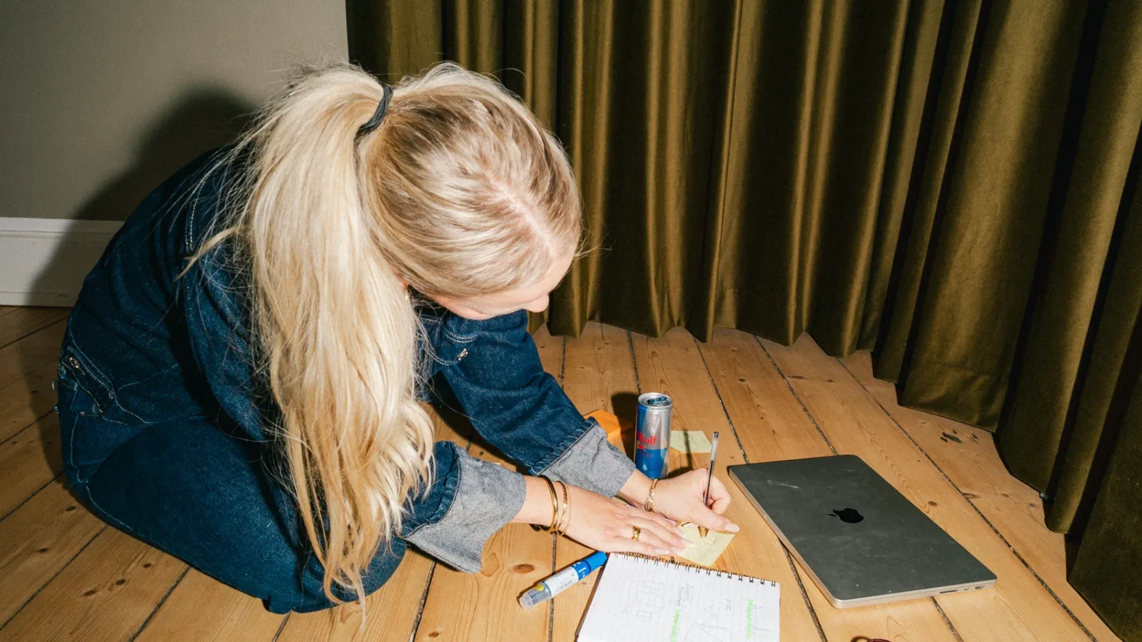 Medarbejder noterer på en post-it ved en notesblok med skitser på gulvet