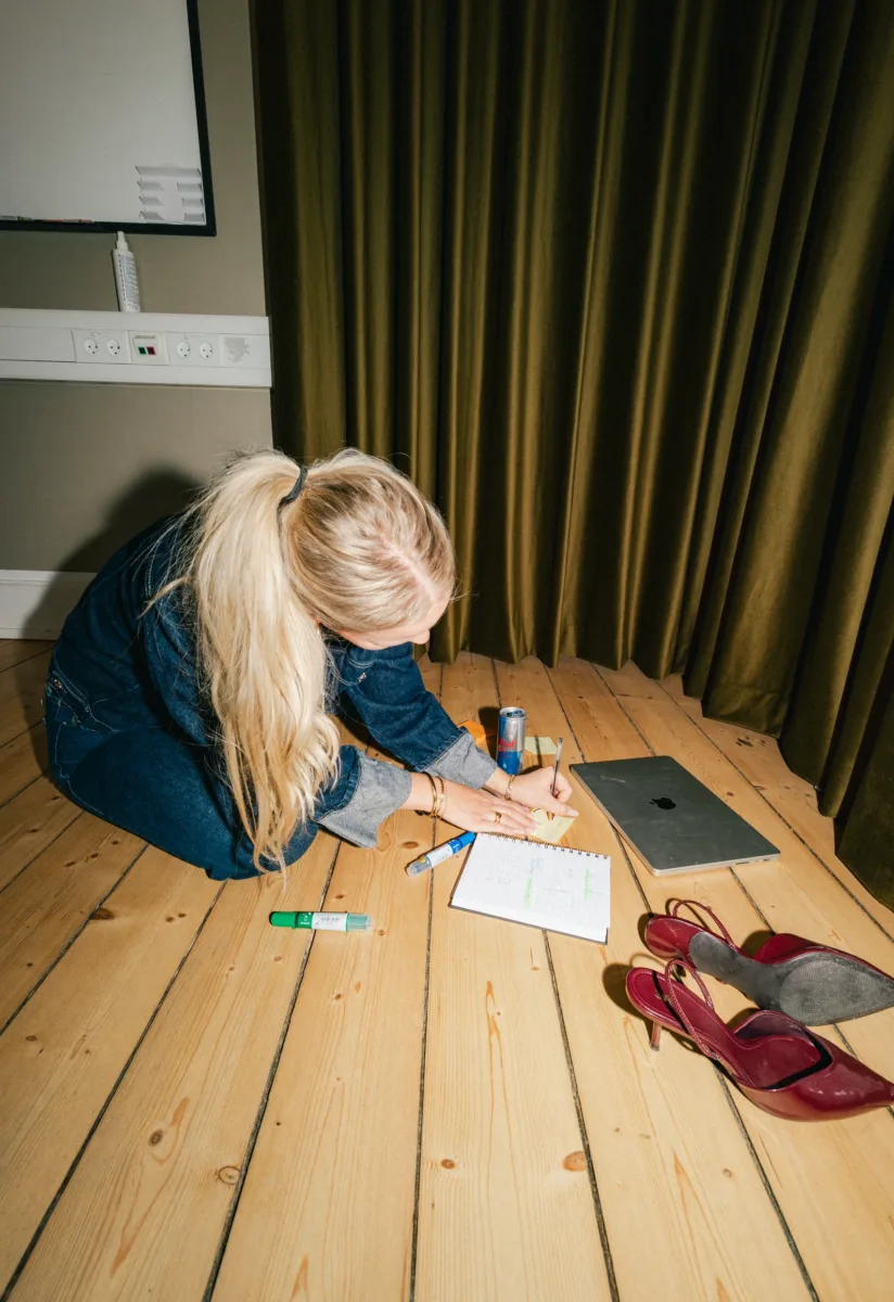 Medarbejder noterer på en post-it ved en notesblok med skitser på gulvet