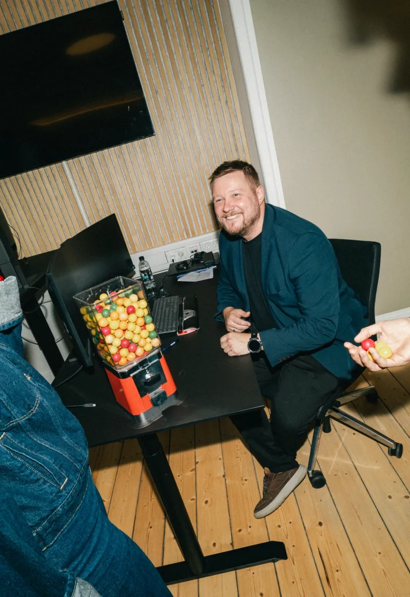 Kolleger taler sammen om en tyggegummiautomat på et skrivebord