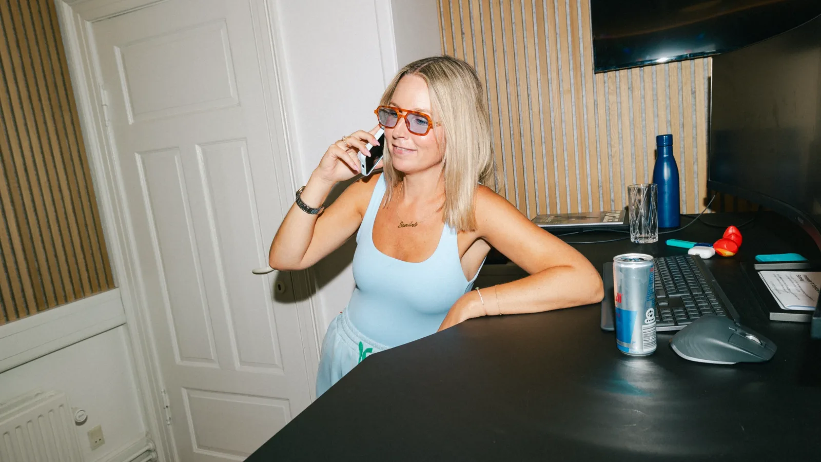 Medarbejder smiler under en telefonsamtale ved sin arbejdsplads