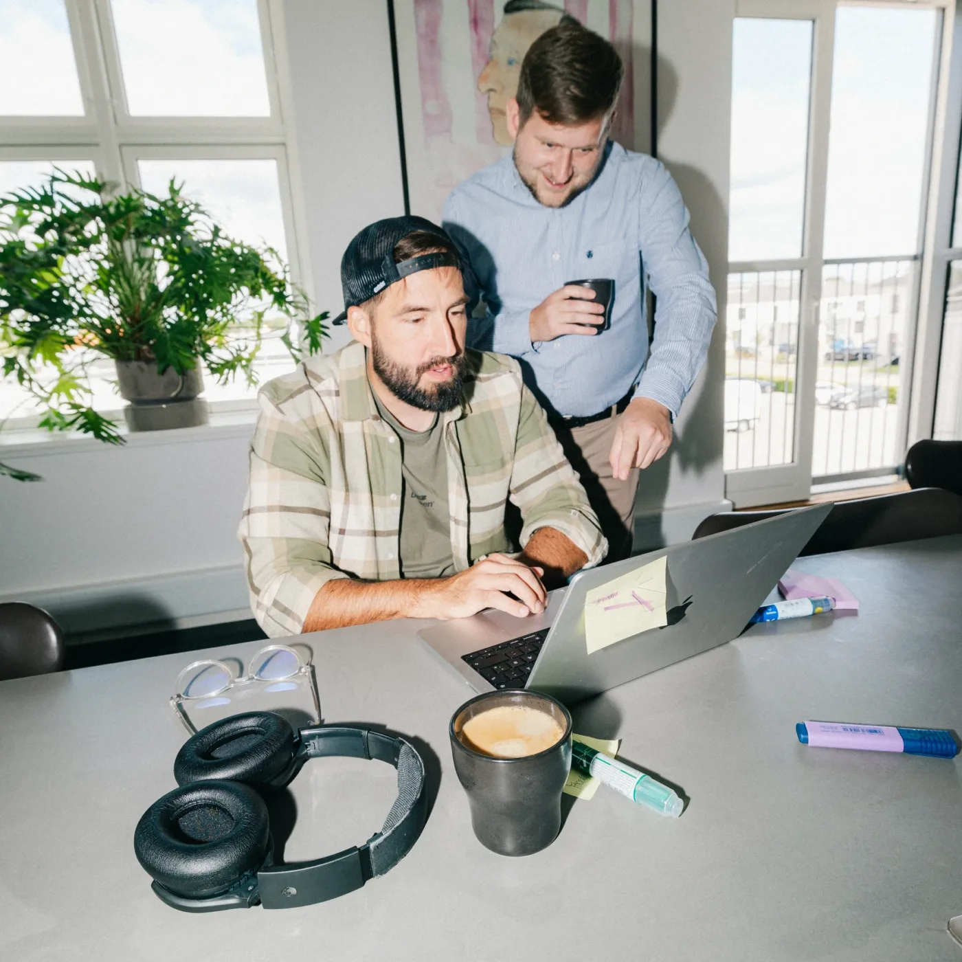 Medarbejder arbejder på en bærbar computer med post-its og markers på bordet