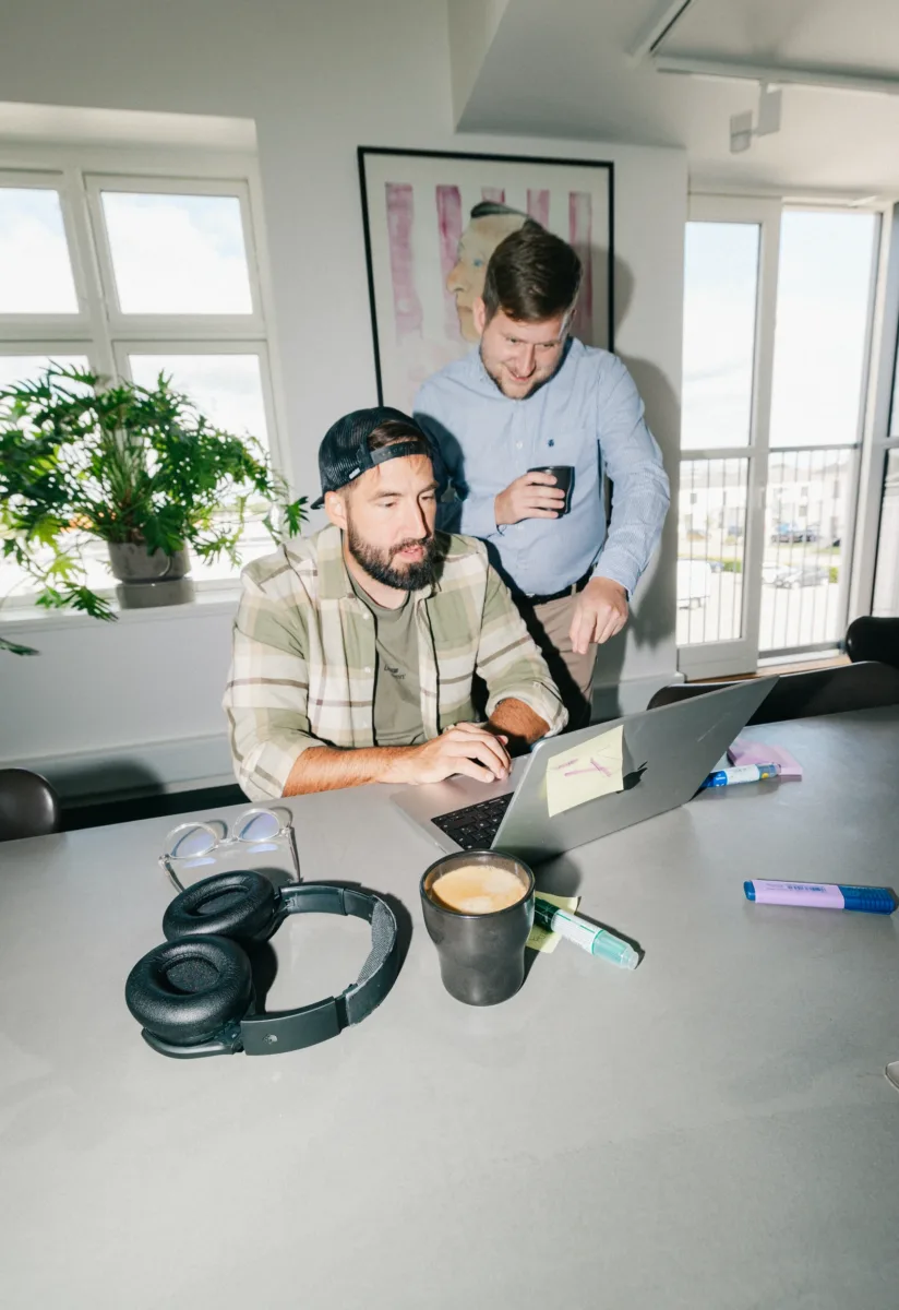 Medarbejder arbejder på en bærbar computer med post-its og markers på bordet