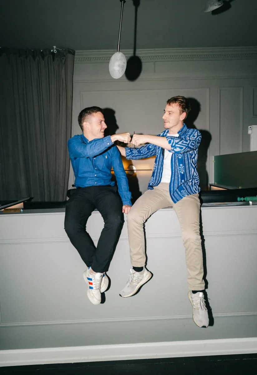 To kolleger sidder på en kant og hilser, mens de kigger på hinanden