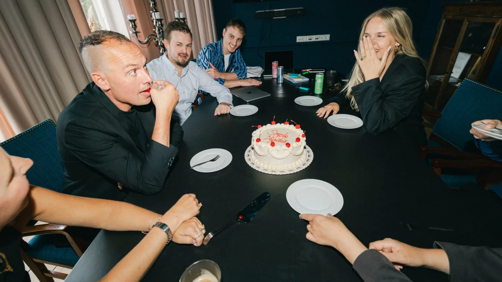 Kolleger samlet om en lagkage med teksten Simple Digital i et mørkeblåt mødelokale