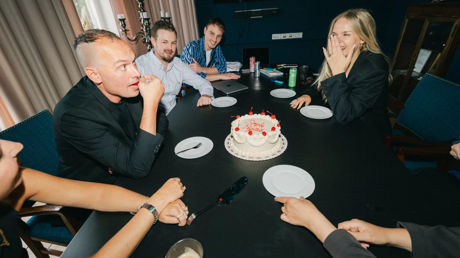 Kolleger reagerer overrasket på en lagkage med teksten Simple Digital