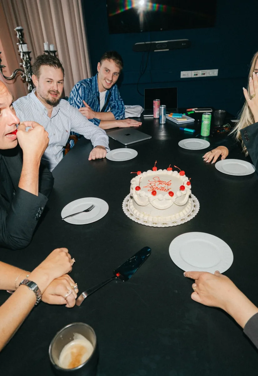 Kolleger reagerer overrasket på en lagkage med teksten Simple Digital